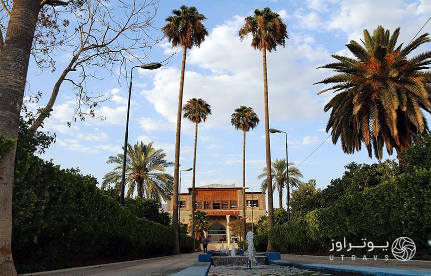 باغ دلگشای شیراز، درختان نخل، حوضی در وسط و عمارتی در انتهای باغ دیده می‌شود. 